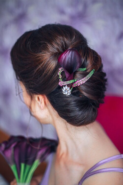 Klassisch hochgesteckte Brautfrisur mit Blüten im Haar.
