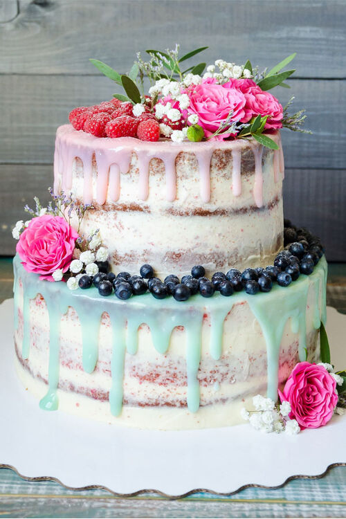 Naked-Cake mit verlaufender Glasur und Früchten als Topping.